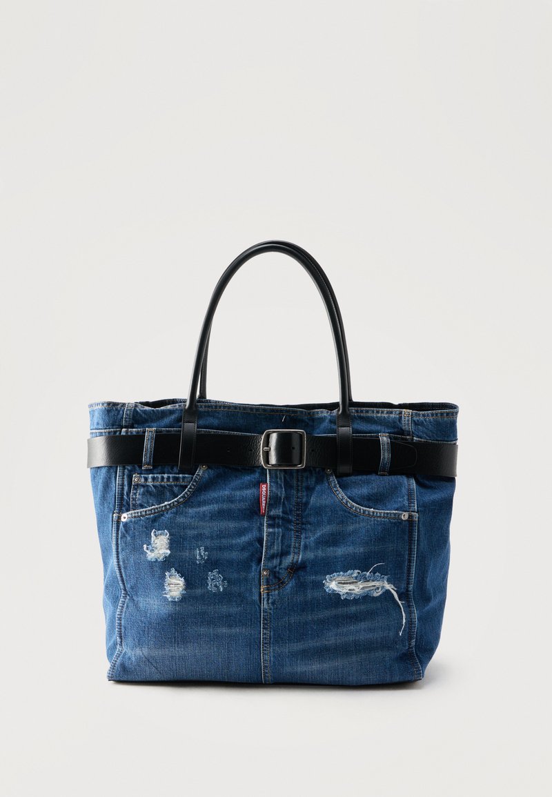 Sac fourre-tout en denim bleu avec détails usés, poignées en cuir noir et une ceinture noire avec une boucle métallique autour du dessus.