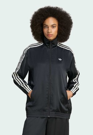 Black satin track jacket with high collar, zip closure, and white three-stripe design on sleeves. Features elastic cuffs and side pockets.