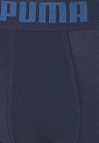 Dunkelblaue Herrenunterhosen mit einem breiten blauen elastischen Bund, der das "PUMA"-Logo trägt. Glattes Material mit verstärkten Nähten.