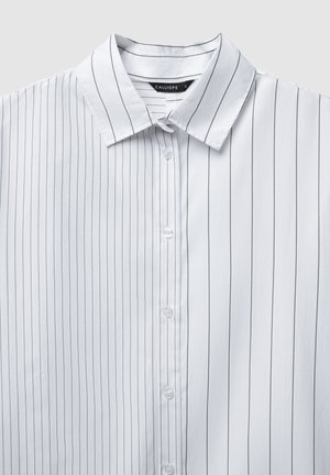 Camicia bianca con righe verticali nere, design con bottoni, colletto a punte e texture liscia. Etichetta del produttore visibile all'interno del colletto.