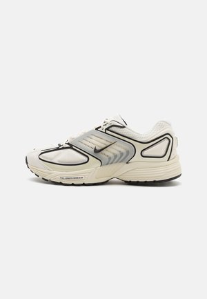Baskets Nike Air pour hommes couleur blanc cassé avec bordure noire, détails en mesh et panneau latéral translucide, présentées en profil gauche sur fond blanc.