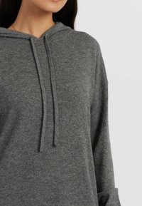 Sweatshirt à capuche grise en tissu doux, avec une coupe décontractée, des cordons de serrage et des poignets côtelés. Design simple sans motifs supplémentaires.