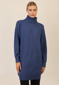 Niebieski oversize'owy sweter z golfem, z prążkowanymi mankietami i dołem. Gładka tekstura, długie rękawy i luźny krój sięgający do połowy uda.