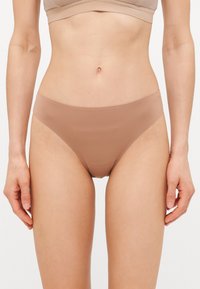 Naadloze, tan bikini slipjes gemaakt van een soepele stof, met een minimalistisch ontwerp, lage taille en geen zichtbare naden.