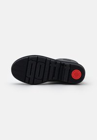 Semelle de chaussure noire avec une texture antidérapante, marquage "grifit" et un logo circulaire rouge indiquant "Comfort Technology Fitflop" sur fond blanc.