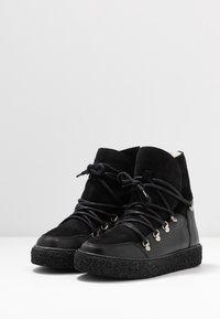 Black high-top sneakers feature a mix of suede and leather, rubber sole, metal eyelets, and laces, with a textured black outsole.