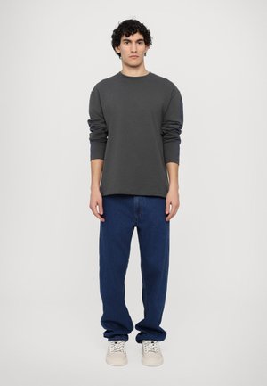 Grå langærmet skjorte med rund hals, parret med blå løstsiddende denim jeans og lyse sneakers. Simpelt design uden synlige mønstre.