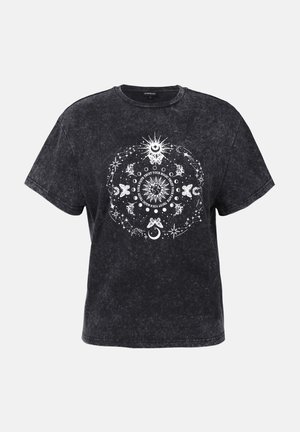T-shirt noir à manches courtes avec une texture délavée, comportant un design graphique central blanc représentant des étoiles, des lunes et des papillons dans un motif circulaire.