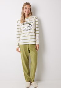 Gestreepte langemouwtop in wit en groen met een Garfield-print, gecombineerd met zachte, olijfgroene pyjamabroek en beige slippers.
