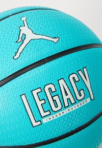 Turkis basketball med teksturert overflate, svart detaljering, et Jumpman-logo og ordet "LEGACY" i fet hvit. Innendørs/utend�ørs bruk.