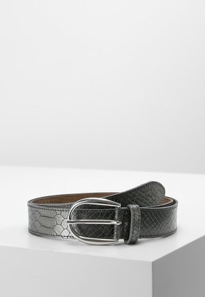 Zwarte gestructureerde leren riem met zilverkleurige ovale gesp, opgerold op een witte ondergrond tegen een effen grijze achtergrond.