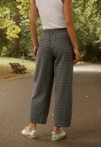 Hoge taille, geruite broek in blauw en wit, met een losse pasvorm en elastische tailleband. Gepaard met zilveren sportschoenen.