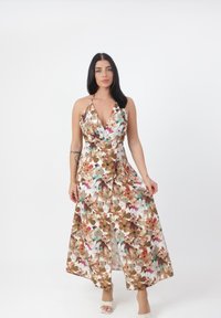 Robe maxi à motif floral avec des tons de marron, vert et rose. Décolleté halter, taille cintrée et tissu fluide avec une fente latérale.