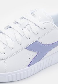 Sneakers bianchi in pelle sintetica con dettagli viola, punta tonda, suola testurizzata e lacci piatti. Piccole perforazioni sui lati.