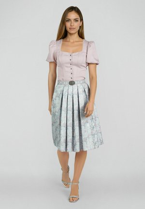 Femme portant un haut rose à manches bouffantes et une jupe plissée argentée à motifs floraux, longueur genou, avec une ceinture décorative, marchant vers l'avant.