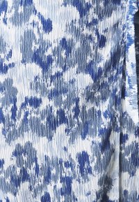 Texturerad tyg med ett blått och vitt abstrakt mönster. Stela linjer skapar en rynkad effekt, med varierande nyanser av blått genom hela.