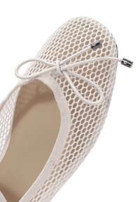 Bailarina de malla blanca ligera con un lazo de encaje. Presenta una punta redondeada, un suave forro interior y una textura sutil con una suela flexible.