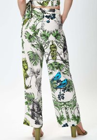 Wide-leg trousers in lightweight fabric featuring a tropical print of green leaves, blue birds, and detailed black and white illustrations.