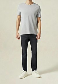 Graues T-Shirt mit kurzen Ärmeln, kombiniert mit schwarzen Slim-Fit-Hosen und weißen Sneakers. Glatter Stoff mit rundem Ausschnitt und dezentem Design.