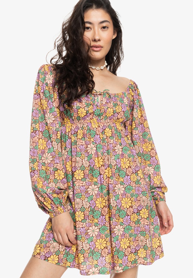 Vestido floral con mangas largas abullonadas; presenta flores multicolores en amarillo, rosa y verde sobre un fondo claro; cintura elástica.