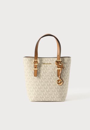 Sac fourre-tout Michael Kors beige clair avec des anses en cuir couleur tan, détails de boucles dorées et pendentif avec logo MK suspendu à une anse.