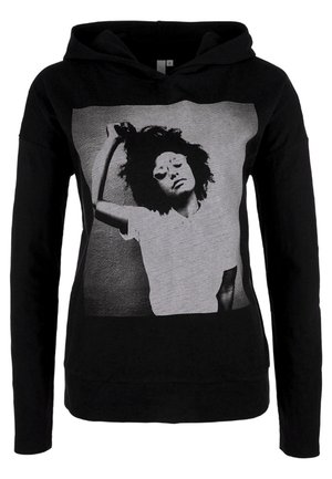 Sort hættetrøje med et monokromt foto af en person med krøllet hår, solbriller og en hvid skjorte, der løfter den ene arm bag hovedet.