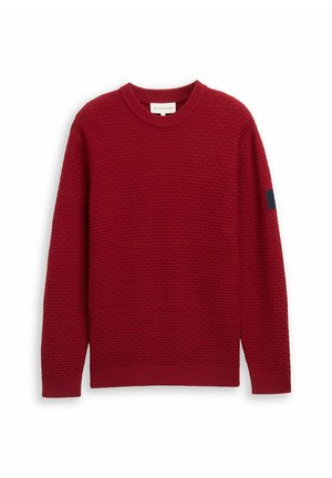 Maglione rosso con texture, colletto a giro, maniche lunghe, polsini a coste e un dettaglio blu scuro sulla manica sinistra.