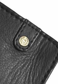 Esquina de billetera de cuero negro con acabado texturizado, que presenta un botón a presión dorado y detalles de costura, destacando durabilidad y diseño.