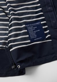 Blauw gestreepte stof met witte strepen, duurzame textuur, waterdichte eigenschappen en een label met details over weerbestendige eigenschappen en gerecyclede materialen.