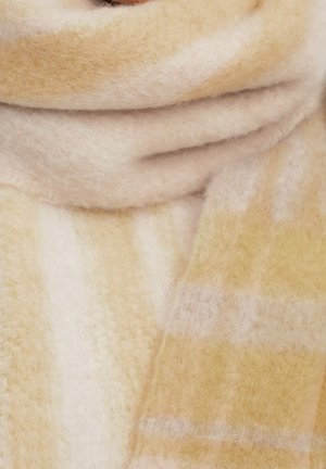 Écharpe douce et épaisse avec un motif à carreaux beige et jaune clair enroulée autour du cou ou de la zone du col.