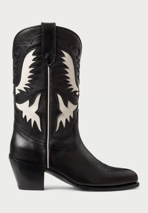 Stivali da cowboy in pelle nera con dettagli angolari bianchi, caratterizzati da una cucitura decorativa, una punta affusolata e un tacco basso impilato.