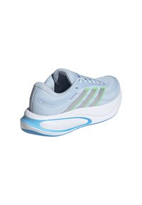 Zapatilla de running azul claro con parte superior de malla, tres franjas verdes y grises, y una suela blanca gruesa con un detalle azul.