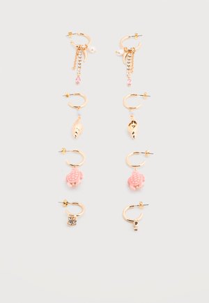 Quatre paires de boucles d'oreilles créoles en or avec des breloques distinctes : strass et perle rose, coquillage doré, tortue rose et grappe de cristaux clairs.