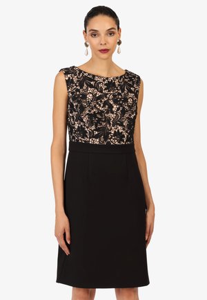 Schwarzes Kleid mit einem Spitzenoberteil mit Blumenmustern und einem festen, taillierten Rock. Ärmelloses Design und knielanger Schnitt. Eleganter Ausschnitt.