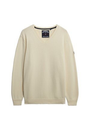 Kremowy sweter typu V-neck z dzianiny, z prążkowanymi mankietami i dołem, z metką Superdry wewnątrz kołnierza oraz małym logo na rękawie.