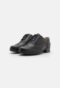 Chaussures Oxford en cuir noir avec détails brogues subtils, bout rond et petit talon carré. Le design à lacets améliore l'ajustement et le confort.