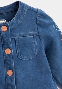 Niebieska kurtka dżinsowa z małą kieszonką na piersi, okrągłym kołnierzykiem, brązowymi guzikami oraz bufkami na długich rękawach z haftowanymi detalami.