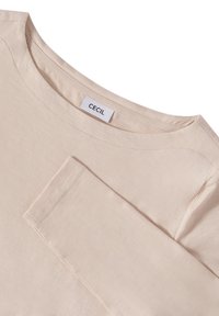 Light beige long-sleeve shirt with a round neckline and visible stitching; fabric appears soft and textured. Label reads "CECIL."