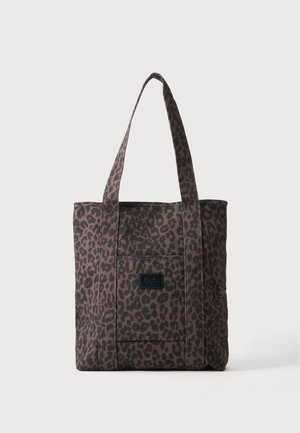 Sac cabas marron avec motif léopard noir, deux longues anses et une poche avant avec une étiquette noire.