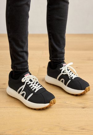 Black sports shoes with white accents and laces; featuring a smooth upper and cushioned sole with textured grip.