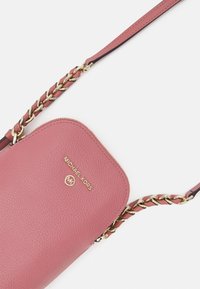Pink leather crossbody bag with gold-tone chain accents, logo embossed on the front, and a textured finish. Adjustable strap included.