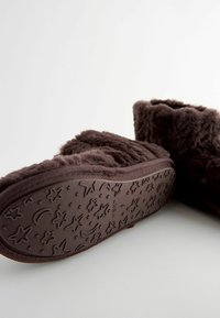 Braune, flauschige Knöchelstiefel mit einem strukturierten Obermaterial und einer Gummisohle, die mit Stern- und Mondmustern versehen ist. Weiches, gemütliches Material für Komfort.