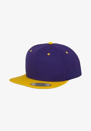 Fialová snapback čiapka so širokým žltým okrajom, s žltým prešívaním a očkami. Vyrobená z látky s hladkou textúrou.