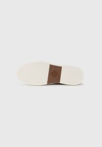 Semelle de chaussure blanche avec un motif de grip texturé, présentant un accent rectangulaire marron au centre. Matériau lisse et durable.