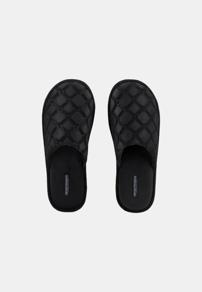 Pantofole nere senza lacci con design trapuntato, tessuto morbido, punta arrotondata e imbottitura nella soletta. Presenta un dettaglio del logo sulla soletta.