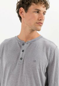 Grå langærmet henley-skjorte i blødt stof med knaplukning og et lille broderet logo på brystet.