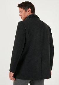 Tumehall villasest villast mantel struktuurse disainiga, sälgutatud kraega, istuva lõikega ja siledast materjalist. Tagaküljel on üks lõhik.