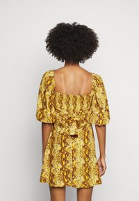 Gul och brun mönstrad miniklänning med puffärmar, fyrkantig halsringning och en rosettdetalj bak. Texturerat tyg med ett ormskinnsmönster.