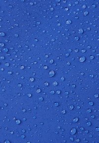 Tissu bleu texturé parsemé de petites gouttes d'eau, mettant en valeur un matériau imperméable avec une finition lisse et mate.