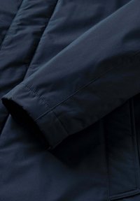 Ärmel einer marineblauen isolierten Jacke mit glatter Textur, sauberer Naht und einem Bund mit weichem Innenfutter.